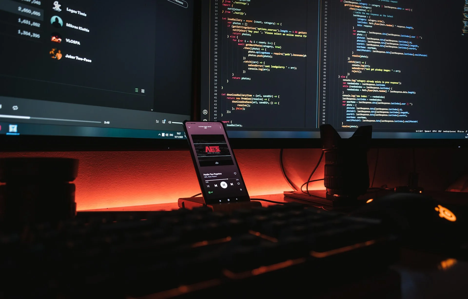 Dark software development workspace with code on multiple screens